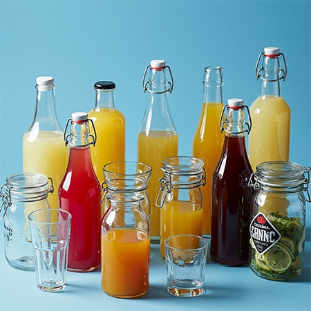 Gastronomie Stimmungsbild: mit Säften und Obst gefüllte Gläser und Flaschen vor einem hellblauen Hintergrund